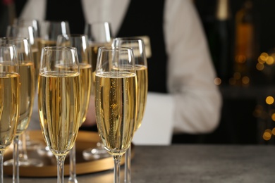 Photo of Glasses of champagne and waiter in restaurant, closeup. Space for text