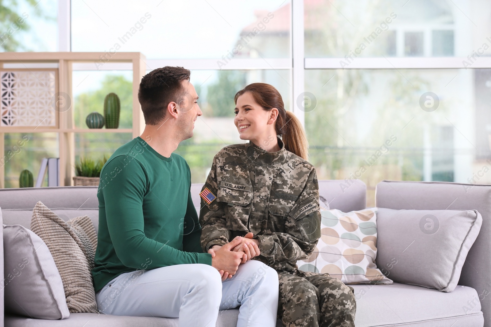 Photo of Woman in military uniform with her husband on sofa at home