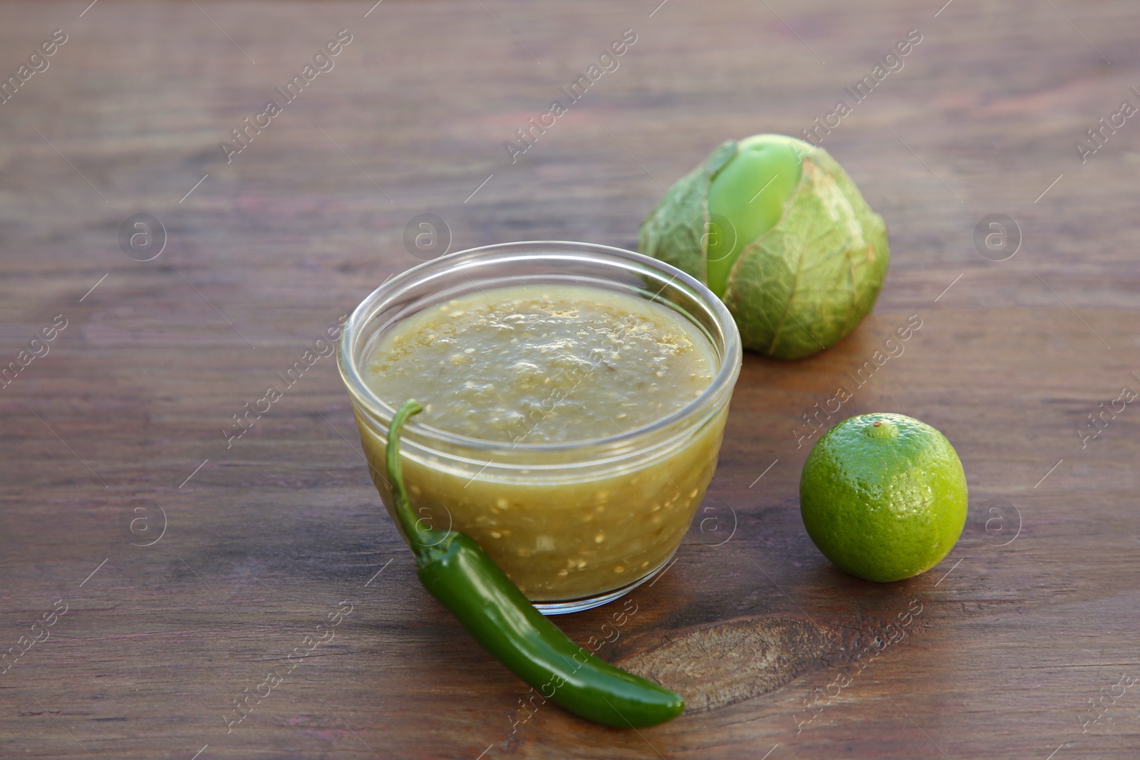 Photo of Tasty salsa sauce and ingredients on wooden table, closeup