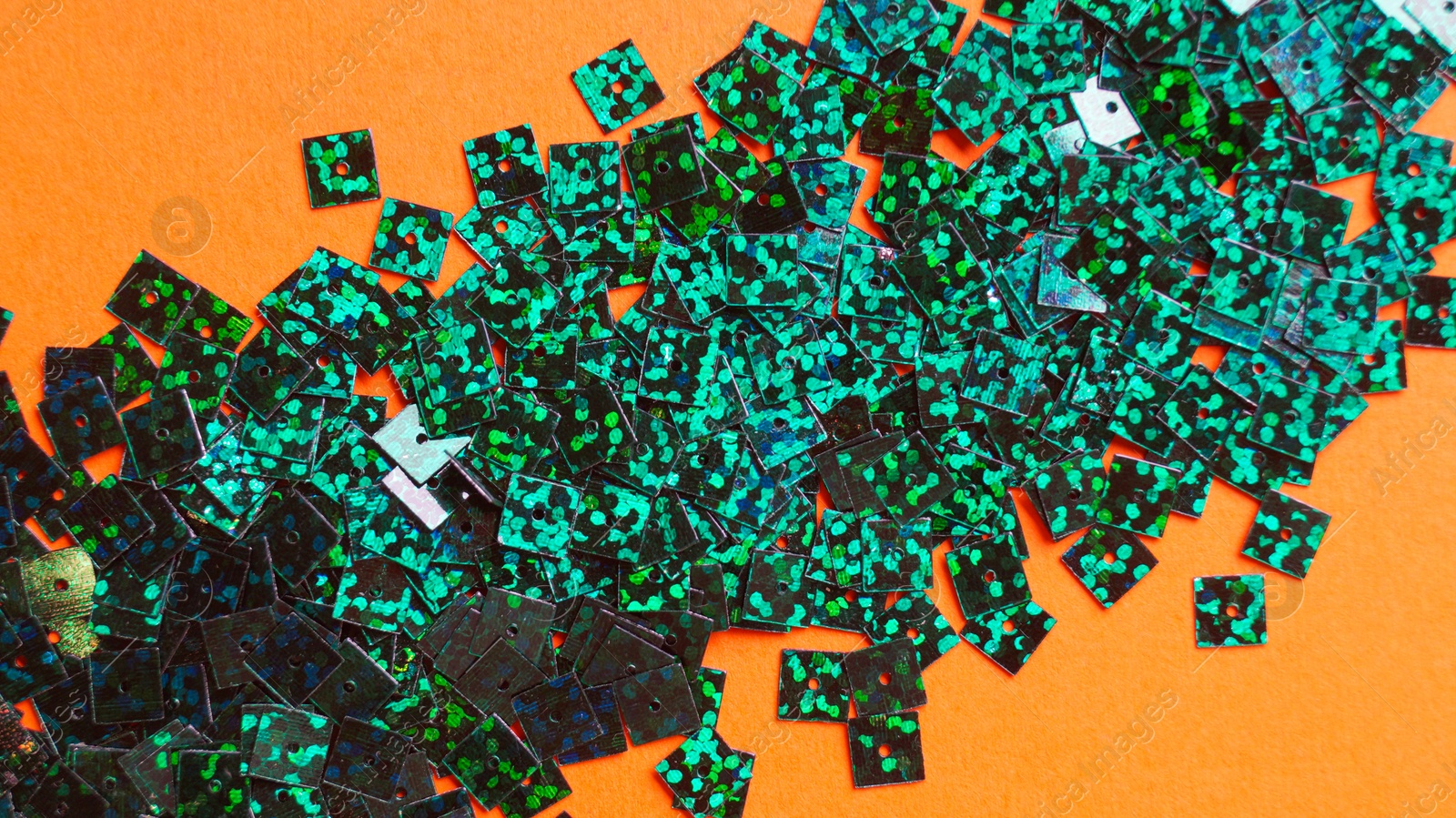 Photo of Many green sequins on orange background, flat lay