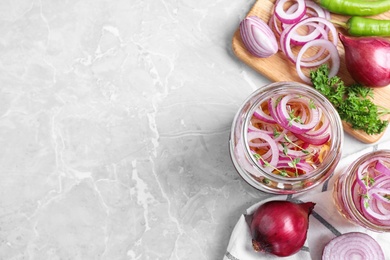 Flat lay composition with jars of pickled onions on marble table. Space for text