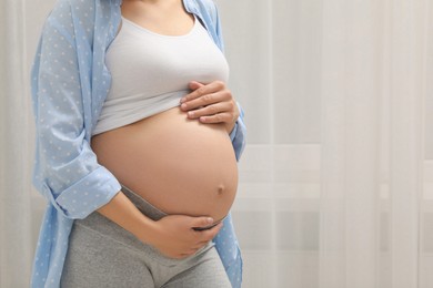 Photo of Pregnant woman indoors, closeup. Space for text