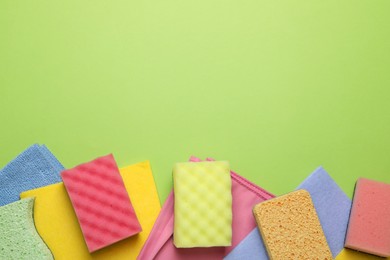 Flat lay composition with sponges on green background. Space for text