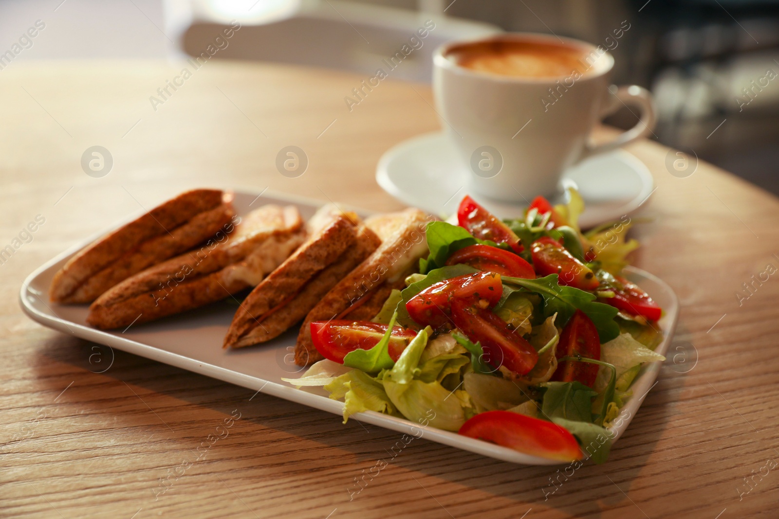 Photo of Plate of delicious toasts with salad and coffee cup on wooden table in cafe