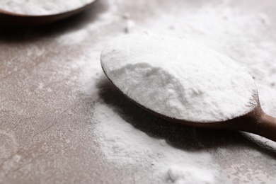 Photo of Spoon with baking soda on table, closeup