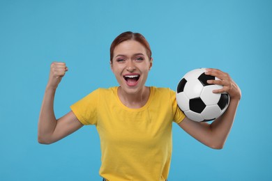 Emotional fan holding football ball and celebrating on light blue background