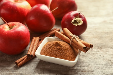 Photo of Fresh apples with cinnamon sticks and powder on wooden table