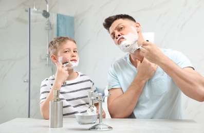 Photo of Dad shaving and son imitating him in bathroom