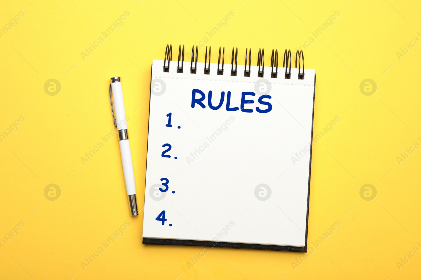 Image of Notebook with list of rules and pen on yellow background, flat lay