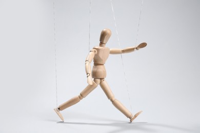 Photo of One wooden puppet with strings on light grey background