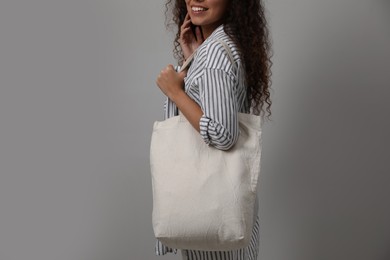 Photo of Happy African-American woman with eco bag on grey background, closeup