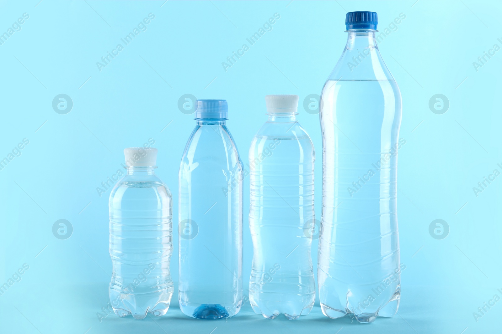 Photo of Row of different plastic bottles with water on color background