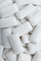 Tasty white chewing gums as background, top view