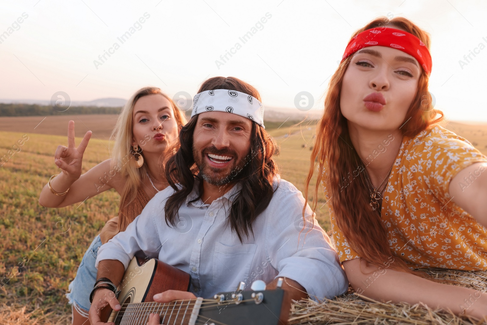 Photo of Happy hippie friends taking selfie in field