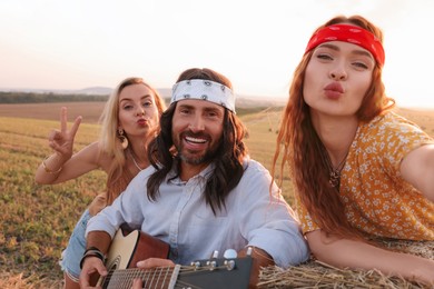 Happy hippie friends taking selfie in field