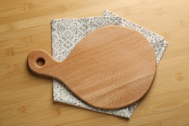 Photo of New cutting board and napkin on wooden table, top view