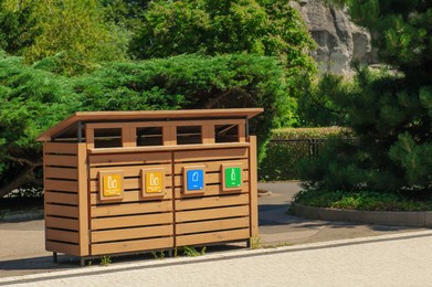 Photo of Wooden recycling bins for waste sorting outdoors