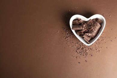 Bowl with chocolate curls and space for text on color background, top view