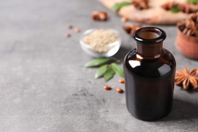 Bottle of essential oil and anise on grey table. Space for text