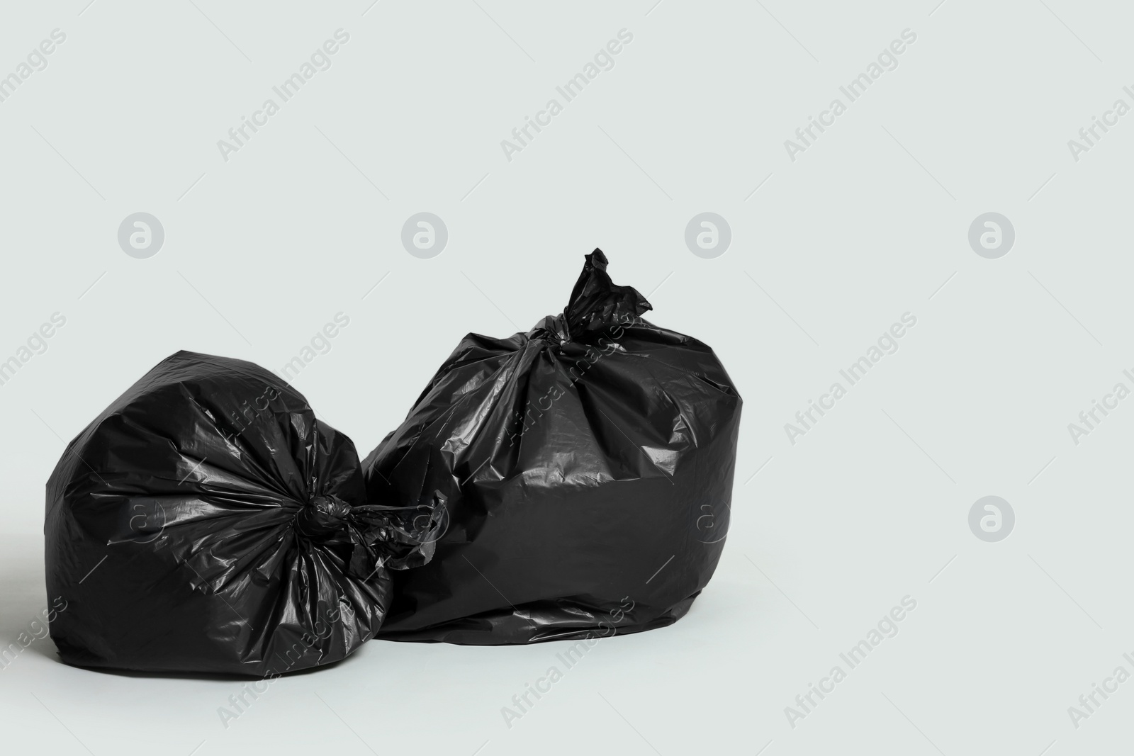 Photo of Trash bags full of garbage on light grey background. Space for text