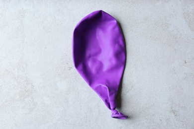 Photo of Purple deflated balloon on grey background, top view