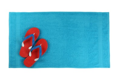 Clean light blue beach towel and flip flops on white background, top view