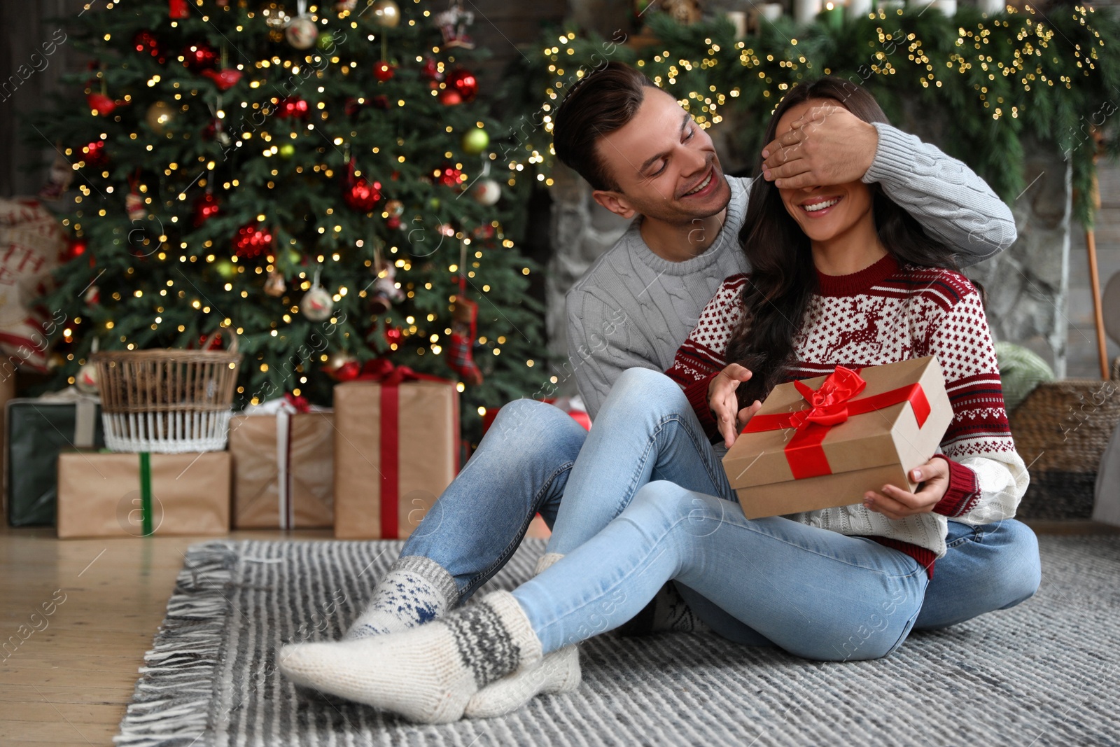 Photo of Happy couple with gift box in living room decorated for Christmas