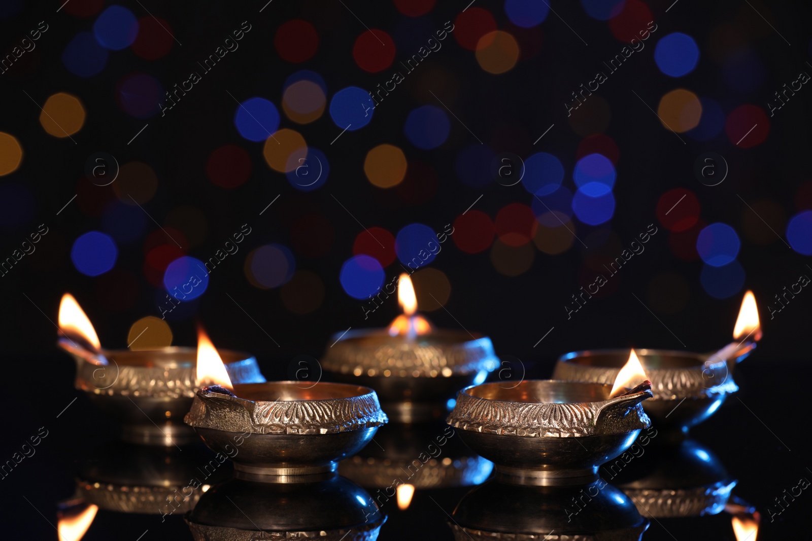 Photo of Many lit diyas on dark background with blurred lights, space for text. Diwali lamps