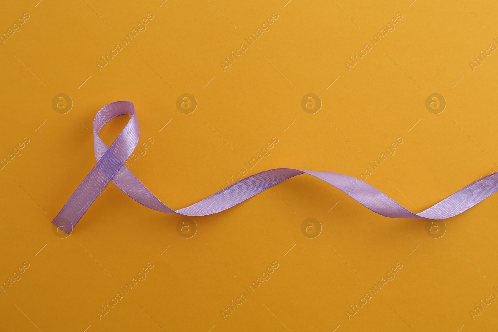 Photo of Violet awareness ribbon on orange background, top view