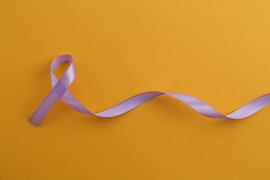 Violet awareness ribbon on orange background, top view