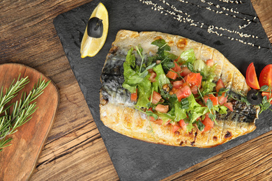 Photo of Delicious grilled fish served on wooden table, flat lay