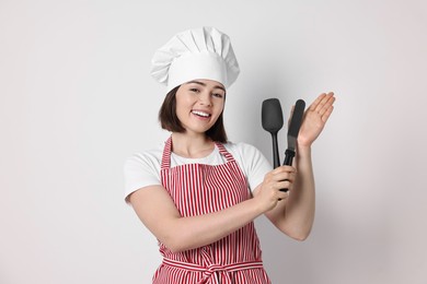 Photo of Happy confectioner holding spatulas on light grey background