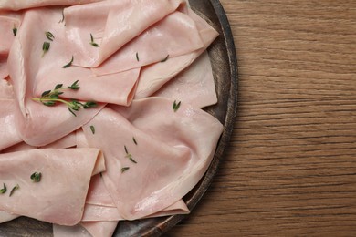 Photo of Delicious ham slices with thyme on wooden table, top view