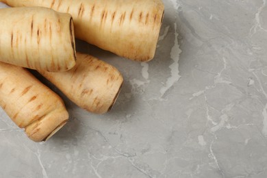 Photo of Many fresh ripe parsnips on grey marble table, flat lay. Space for text