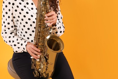 Photo of Woman with saxophone on yellow background, closeup. Space for text