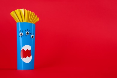 Photo of Funny blue monster on red background, space for text. Halloween decoration
