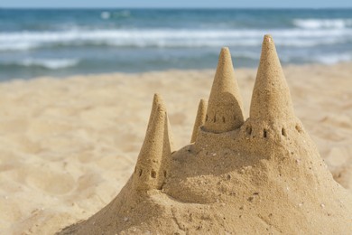 Photo of Beach with sand castle near sea on sunny day. Space for text