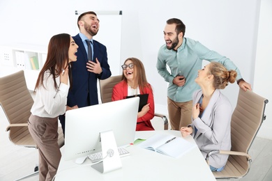 Photo of Group of office employees laughing in conference room