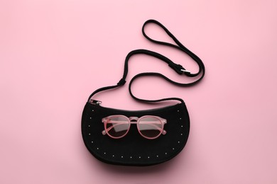Stylish woman's bag and sunglasses on pink background, top view