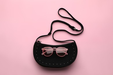 Photo of Stylish woman's bag and sunglasses on pink background, top view