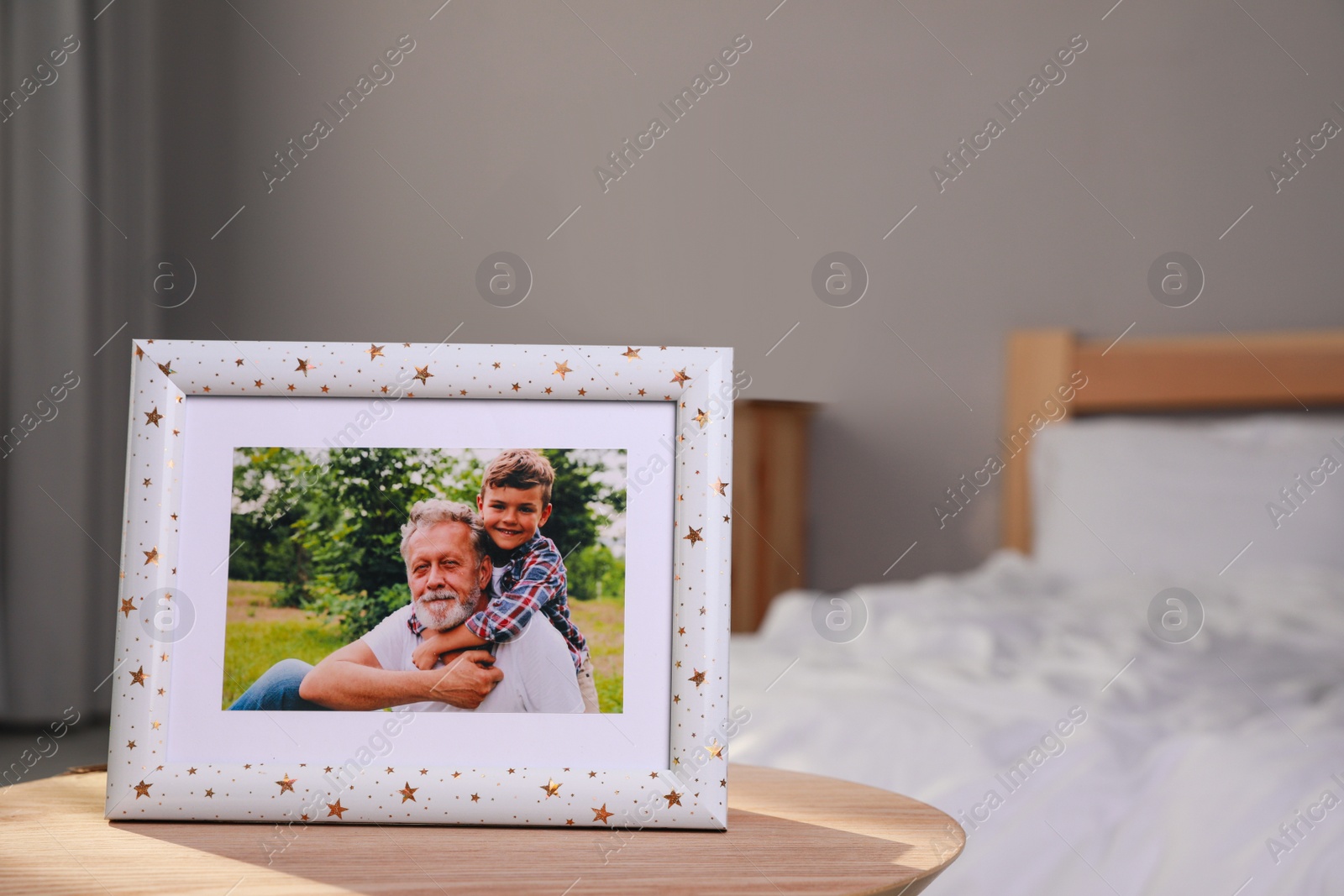 Photo of Framed family photo on wooden table in bedroom. Space for text