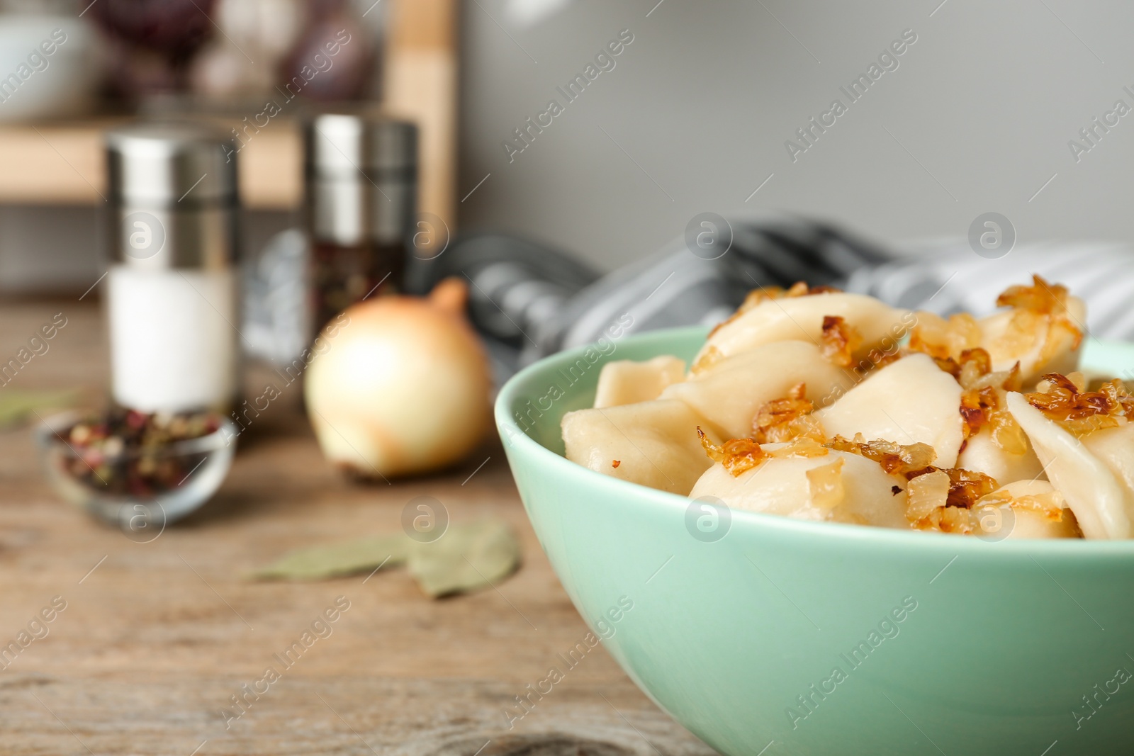 Photo of Delicious cooked dumplings with fried onion on wooden table, closeup. Space for text