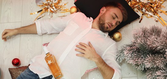 Image of Drunk man sleeping on floor in messy room after New Year party, above view. Banner design