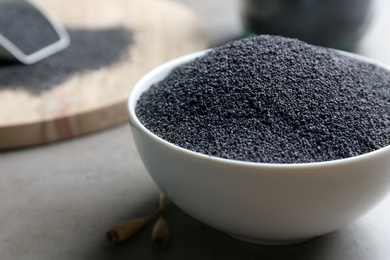 Photo of Poppy seeds in bowl on grey table