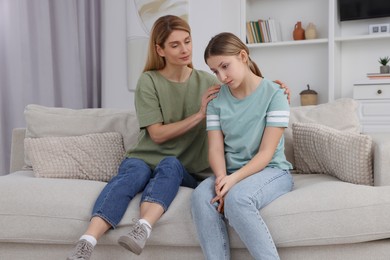 Photo of Mother comforting her upset teen daughter at home