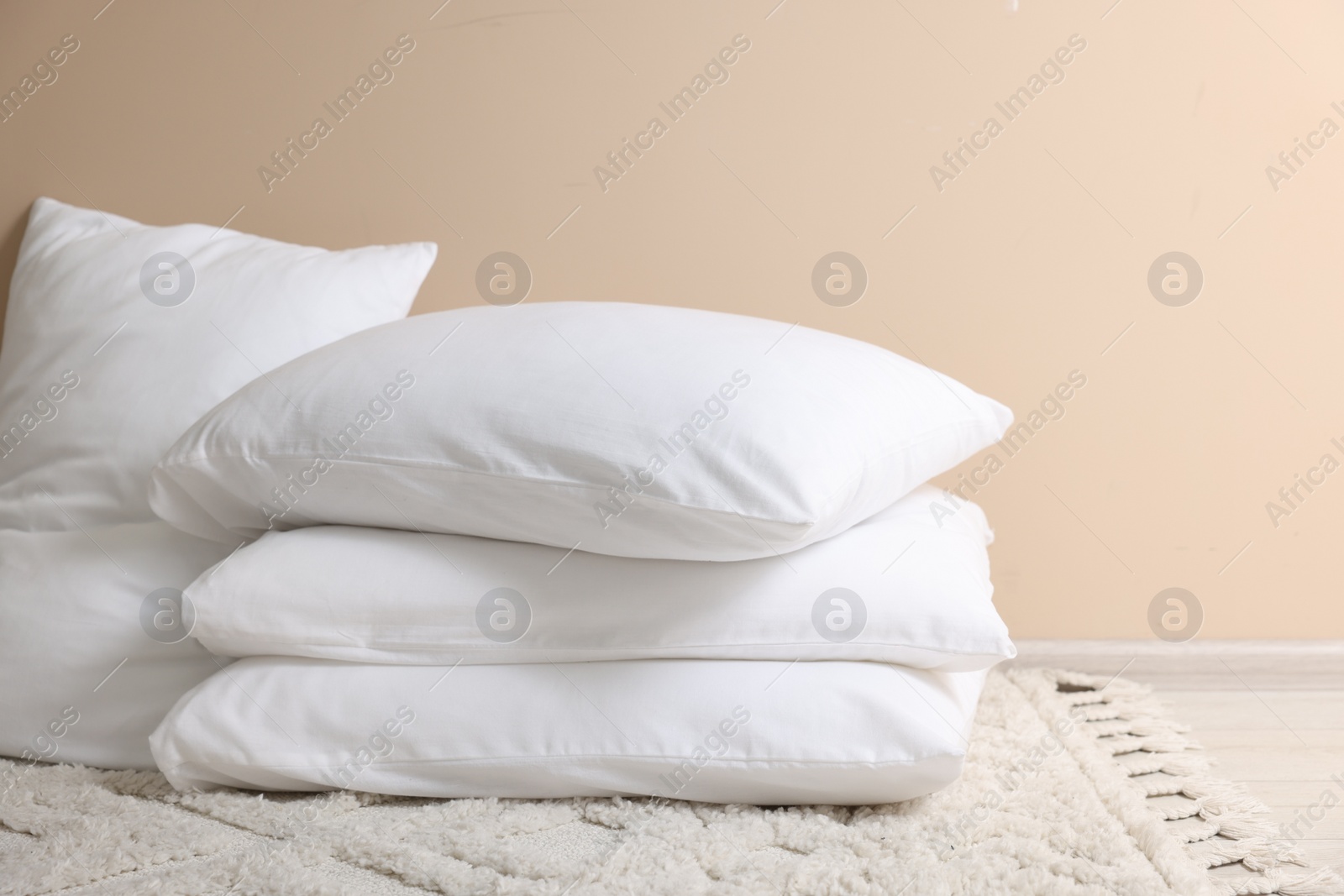Photo of Soft white pillows near beige wall indoors. Space for text