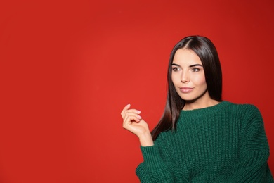 Pretty woman wearing warm sweater on red background. Space for text