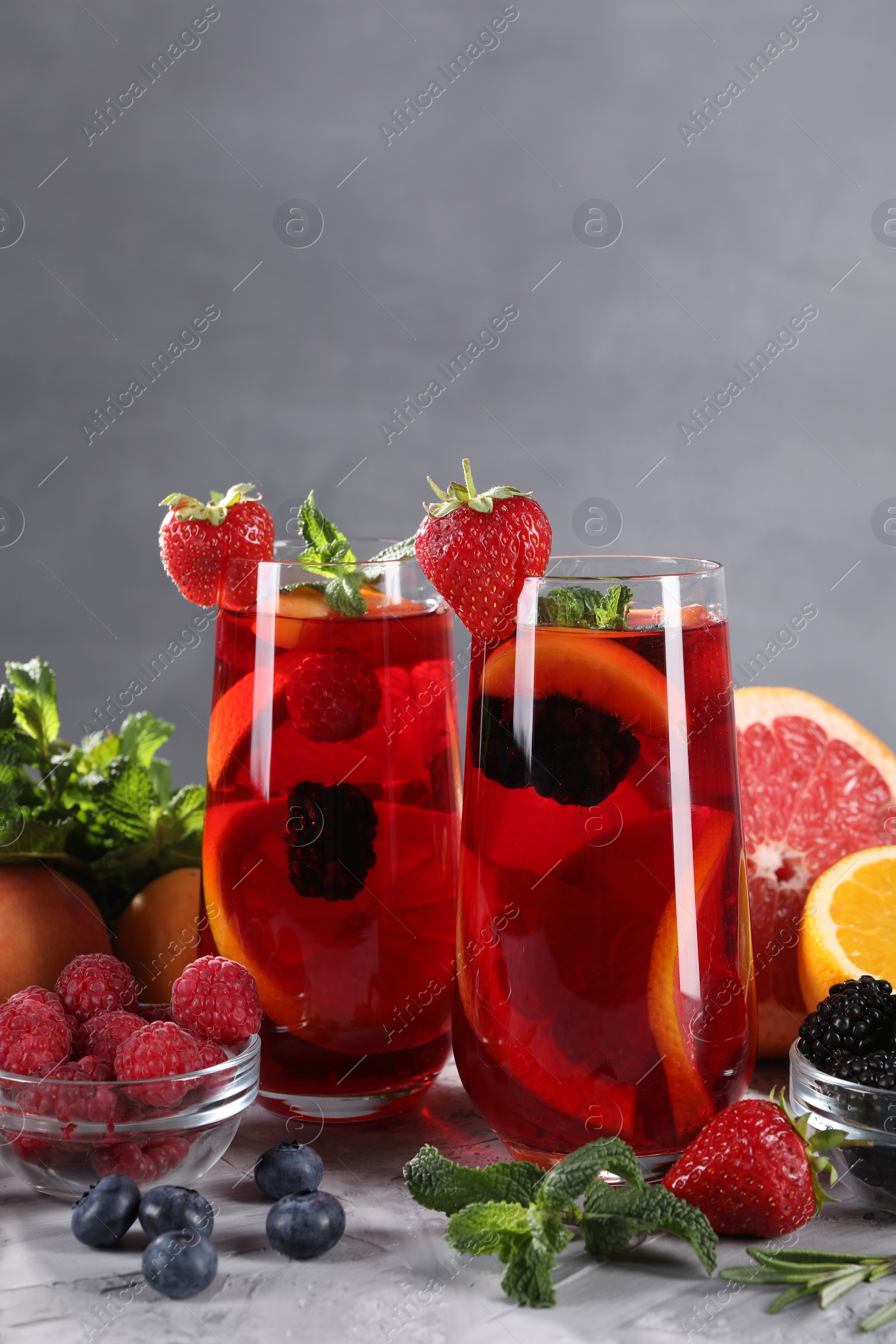Photo of Delicious refreshing sangria with fresh fruits and berries on light grey table, space for text