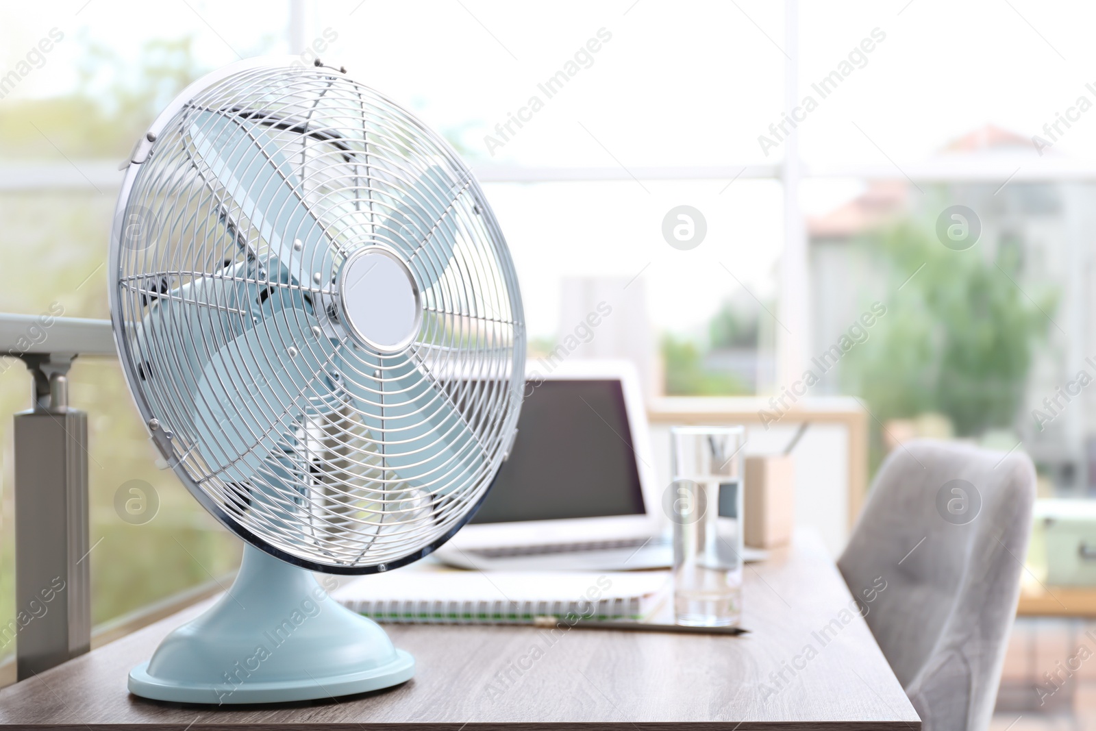 Photo of Modern fan on wooden table in office, space for text. Summer heat