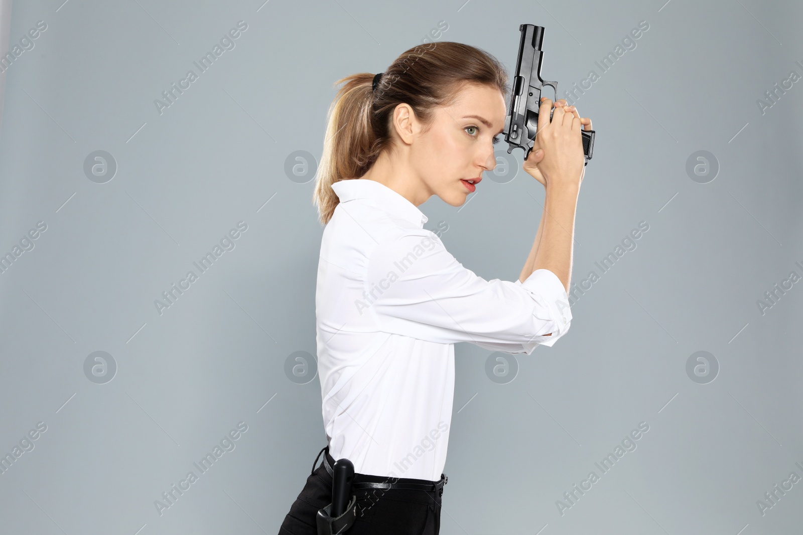 Photo of Female security guard in uniform with gun on grey background